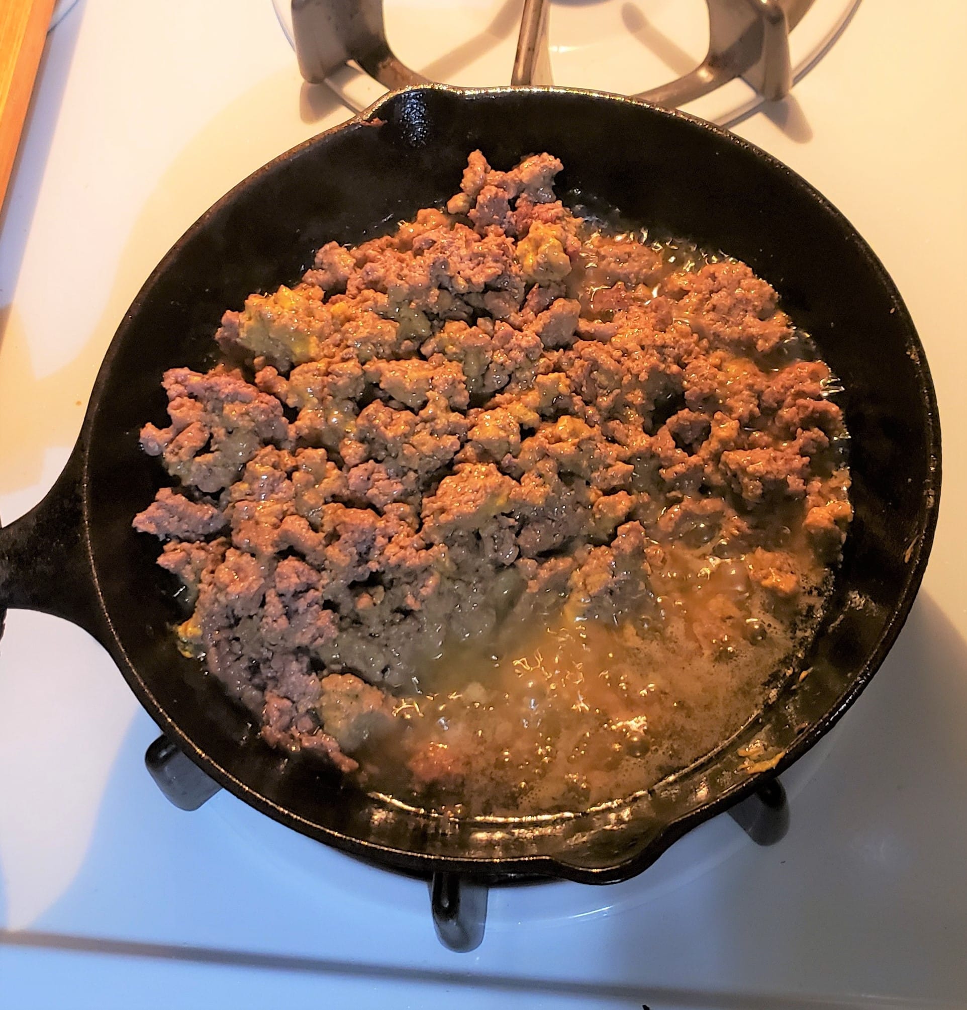 Cast iron skillet with ground beef showing all the grease